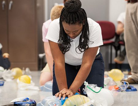 woman practices CPR on dummy