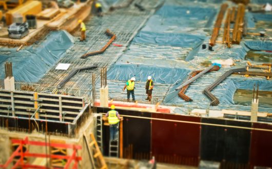 Wide shot of a construction site with three workers in safety gear